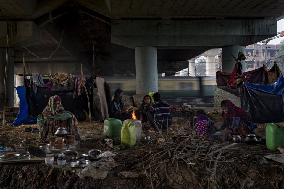 Homeless people rest on a patch of land under an overpass next to a railway track on a cold morning in New Delhi, Dec. 30, 2022. The harsh winter is blamed for killing scores of homeless people and leaving tens of thousands of others shivering on the streets. (AP Photo/Altaf Qadri)