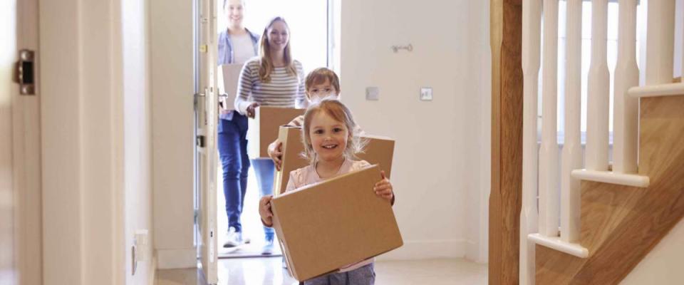 Family Carrying Boxes Into New Home On Moving Day