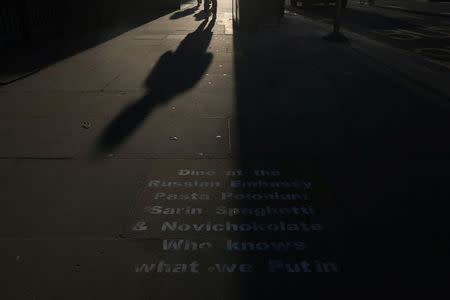 People walk past graffiti sprayed on the pavement near the entrance to the Russian embassy and ambassador's residence in London, Britain, March 15, 2018. REUTERS/Hannah McKay