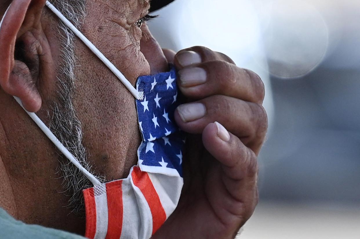 A man adjusts his American flag face mask on July 19, 2021 on a street in Hollywood, California, on the second day of the return of the indoor mask mandate in Los Angeles County due to a spike in coronavirus cases. - The US surgeon general on July 18 defended a renewed mask mandate in Los Angeles, saying other areas may have to follow and adding that he is 