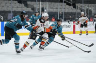 Anaheim Ducks center Sam Carrick (39) moves the puck up the ice past San Jose Sharks' Erik Karlsson (65) and Jeffrey Truchon-Viel (63) during the second period of an NHL hockey game, Monday, April 12, 2021, in San Jose, Calif. (AP Photo/Tony Avelar)