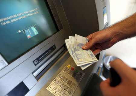 A man withdraws sixty Euros, the maximum amount allowed after the imposed capital controls in Greek banks, at a National Bank of Greece ATM in Piraeus port near Athens, Greece June 30, 2015. REUTERS/Yannis Behrakis