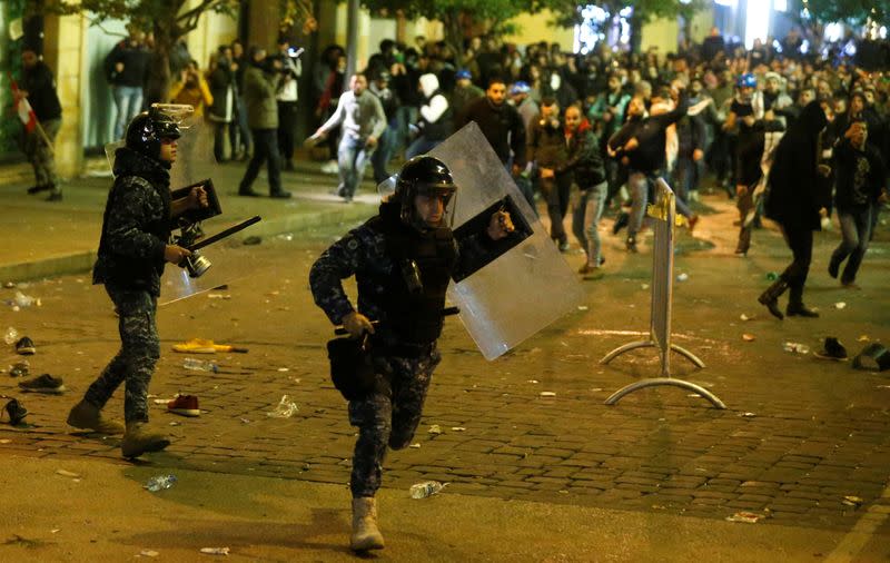 A riot police runs for cover during anti government protests in Beirut