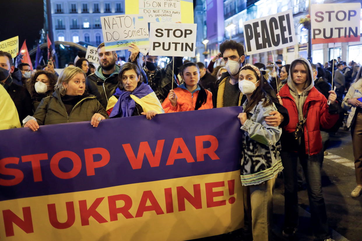 Protesters hold a banner and placards during a protest, after Russia launched a massive military operation against Ukraine, at Puerta del Sol square in Madrid, Spain, February 25, 2022. REUTERS/Jon Nazca