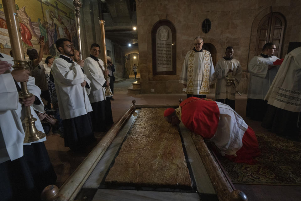 Latin Patriarch of Jerusalem Pierbattista Pizzaballa kisses the Stone of Unction, which is traditionally claimed as the stone where Jesus' body was prepared for burial, before celebrating the Easter Sunday Mass at the Church of the Holy Sepulchre, where many Christians believe Jesus was crucified, buried and rose from the dead, in the Old City of Jerusalem, Sunday, March 31, 2024. (AP Photo/Leo Correa)