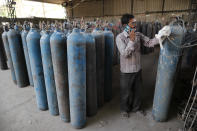 A worker refills medical oxygen cylinders at a charging station on the outskirts of Prayagraj, India, Friday, April 23, 2021. India put oxygen tankers on special express trains as major hospitals in New Delhi on Friday begged on social media for more supplies to save COVID-19 patients who are struggling to breathe. India's underfunded health system is tattering as the world's worst coronavirus surge wears out the nation, which set another global record in daily infections for a second straight day with 332,730. (AP Photo/Rajesh Kumar Singh)