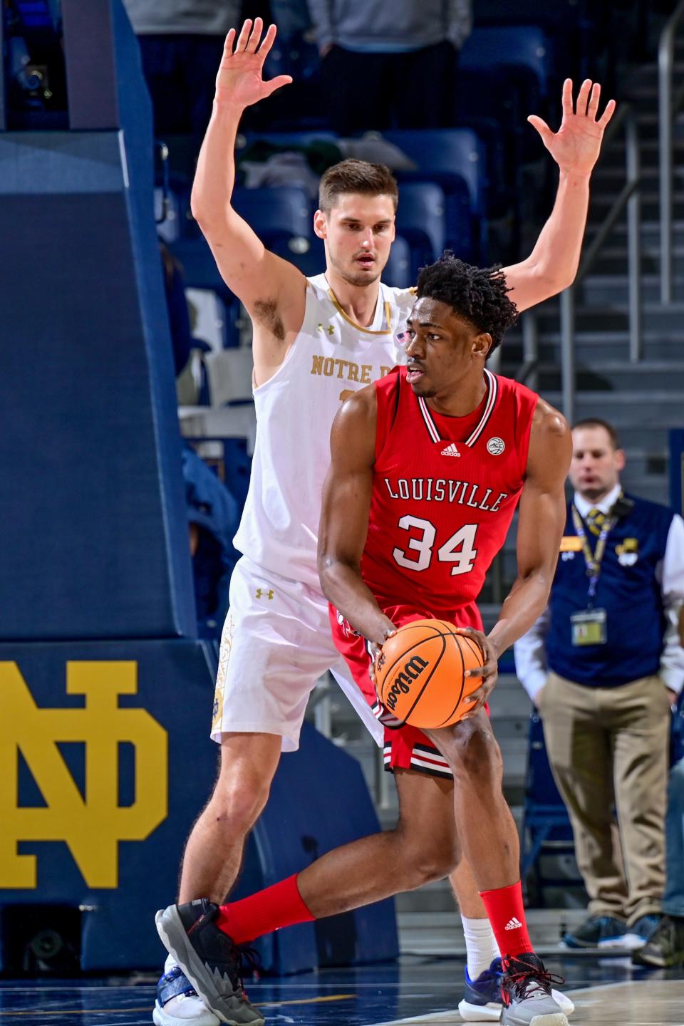 Jan 28, 2023; South Bend, Indiana, USA; Louisville Cardinals forward Emmanuel Okorafor (34) controls the ball against Notre Dame Fighting Irish forward Nate Laszewski (14) in the second half at the Purcell Pavilion. Mandatory Credit: Matt Cashore-USA TODAY Sports