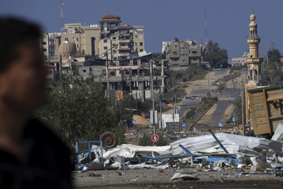 Palestinian man walks on the rubble of destroyed building after an Israeli airstrike, while others fleeing to the southern Gaza Strip along Salah al-Din Street, outskirts of Gaza City, Saturday, Nov. 18, 2023. (AP Photo/Adel Hana)