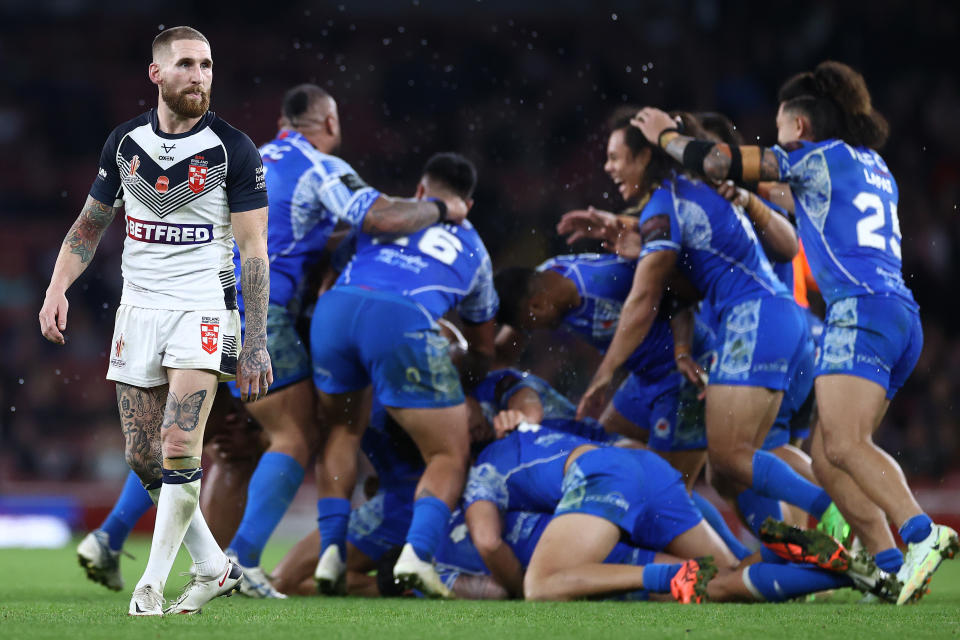 LONDON, ENGLAND - NOVEMBER 12: England captain Sam Tomkins reacts after his side lose out to a golden point drop goal defeat as the Samoa players celebrate during the Rugby League World Cup Semi-Final match between  England/Papua New Guinea and Tonga/Samoa at Emirates Stadium on November 12, 2022 in London, England. (Photo by Michael Steele/Getty Images)