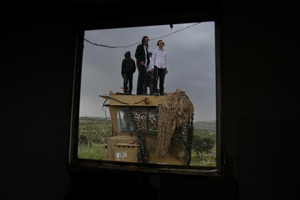 Israeli settlers stand in the outpost of Eviatar in the West Bank, Monday, April 10, 2023. Thousands led by hardline ultranationalist Jewish settlers marched to the unauthorized settlement outpost Eviatar in the northern West Bank that was cleared by the Israeli government in 2021, protected by a large contingent of Israeli soldiers and police. (AP Photo/Ariel Schalit)