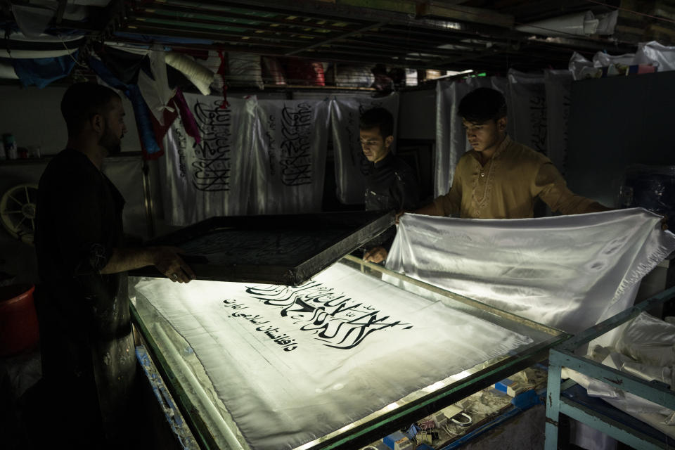 Workers hand print Taliban flags in a small workshop in Kabul's Jawid market, Afghanistan, Sunday, Sept. 12, 2021. The flag shop, tucked away in the courtyard of a Kabul market, has documented Afghanistan’s turbulent history over the decades with its ever-changing merchandise. Now the shop is filled with white Taliban flags, emblazoned with the Quran's Muslim statement of faith, in black Arabic lettering. (AP Photo/Bernat Armangue)