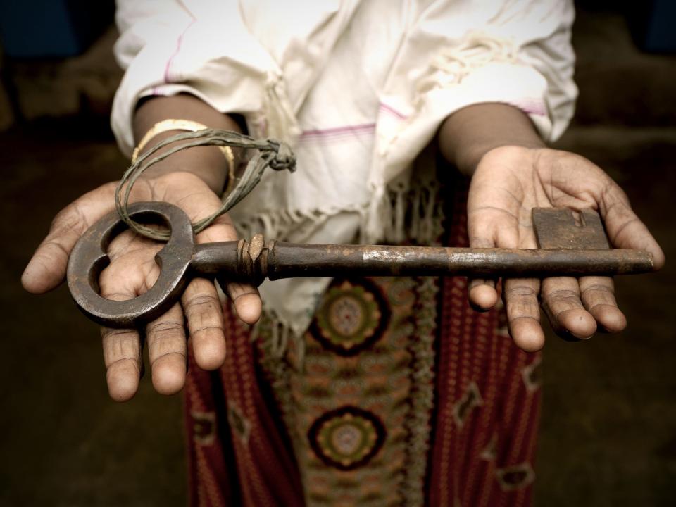 A person uses two hands to hold out one of the keys to a Chettinad mansion.