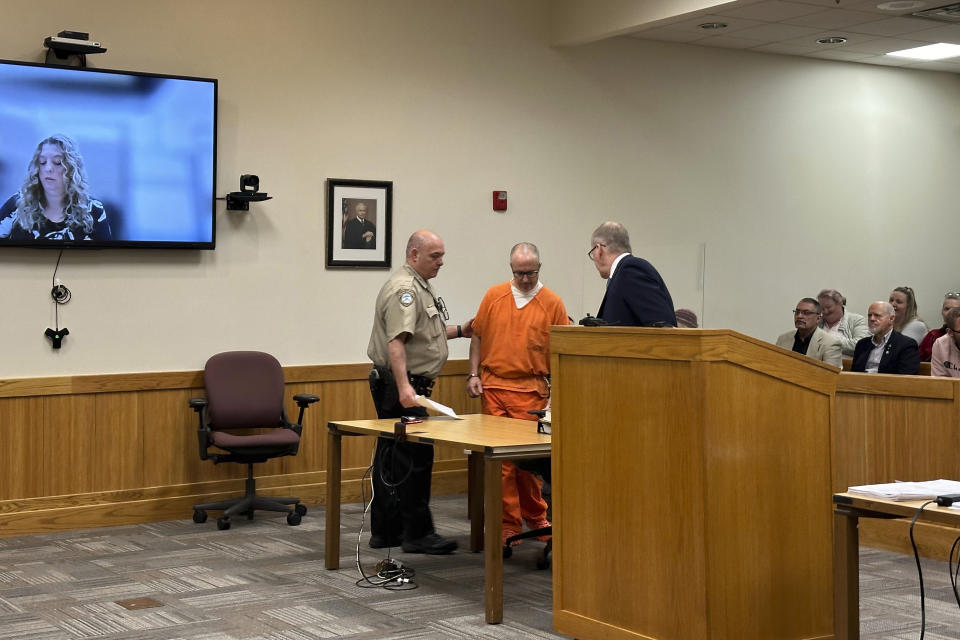 Barry Cadden, center, enters court in Livingston County, Mich., Thursday, April 18, 2024. Cadden operated New England Compounding Center, a Massachusetts specialty pharmacy, which caused a national meningitis outbreak in 2012. On Thursday, the involuntary manslaughter sentencing for Cadden was suddenly postponed when lawyers looked up and saw a different judge on the bench. (AP Photo/Ed White)