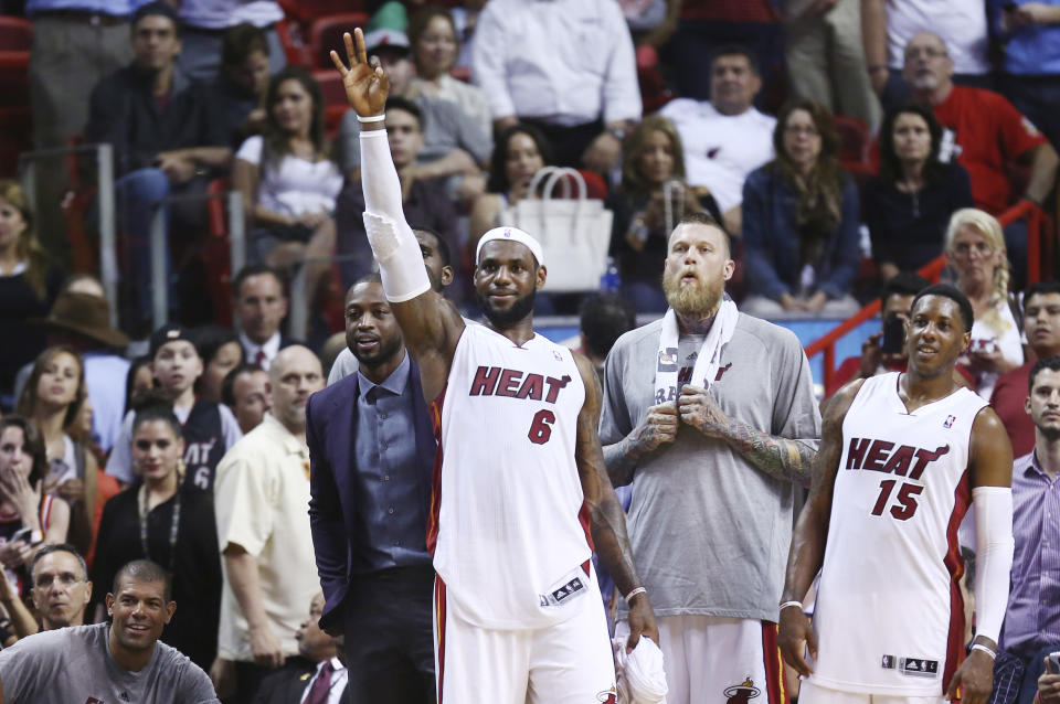 Miami Heat players Dwyane Wade, left, LeBron James (6), Chris Andersen and Mario Chalmers (15) watch the end of an NBA basketball game in Miami, Monday, March 3, 2014 against the Charlotte Bobcats. LeBron James scored a team recond of 61 points. The Heat won 124-107. (AP Photo/J Pat Carter)