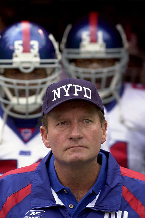 FILE - New York Giants coach Jim Fassel wears a New York Police Department cap while pausing during a moment of silence for those killed at the World Trade Center during the Sept. 11 terrorist attacks, before an NFL football game against the Kansas City Chiefs at Arrowhead Stadium in Kansas City, Mo., in this Sunday, Sept. 23, 2001, file photo. Fassel, a former coach of the New York Giants who was named NFL coach of the year in 1997 and led the team to the 2001 Super Bowl, has died. He was 71. Fassel's son, John, confirmed the death to the Los Angeles Times on Monday, June 7, 2021. According to the Los Angeles Times, Fassel was taken to a hospital in Las Vegas with chest pains and died of a heart attack. (AP Photo/Charlie Riedel, FIler)