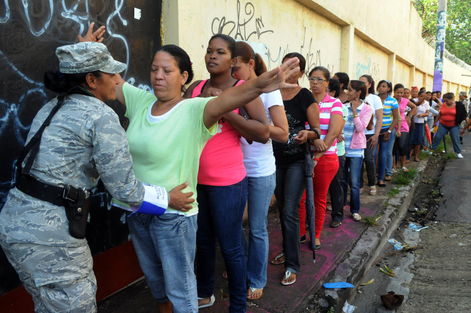 A Dominican Republic soldier frisks a voter waiting in the women's line to cast their ballots during the presidential election in Santo Domingo, Dominican Republic, Sunday May 20, 2012. (AP Photo/Manuel Diaz)