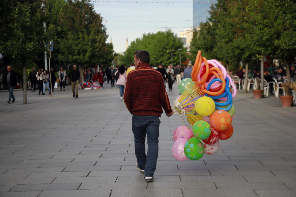 A street vendor carries balloons in main square of Kosovo capital Pristina on Monday, Oct. 7, 2019. Kosovo's opposition parties have won a snap election, overcoming the former independence fighters who have governed the country since its war 20 years ago. With 96% of the votes counted Monday the left-wing Movement for Self-Determination Party, or LVV, has 26% of the votes, one percentage point more than the conservative Democratic League of Kosovo, or LDK, also formerly in opposition. (AP Photo/Visar Kryeziu)