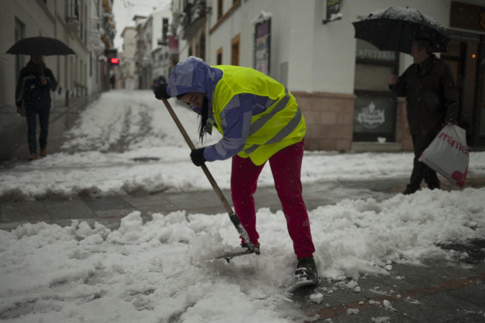 A woman clears snow accumulated on the street after snowfall in the city of Ronda, southern Spain, Thursday, Jan. 19, 2017. The schools of Ronda, one of the most historical towns of Andalusia, suspended their classes Thursday and traffic has been interrupted on several highways due to the intense snowfall that has fallen during the night. A cold spell has reached Europe with temperatures plummeting far below zero. (AP Photo/Javier Gonzalez)