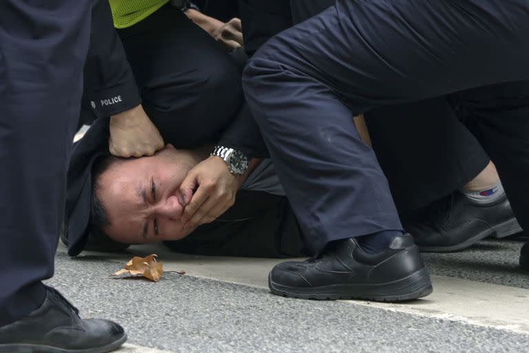 En esta foto tomada el domingo 27 de noviembre de 2022, policías inmovilizan y arrestan a un manifestante durante una protesta en una calle de Shanghái, China