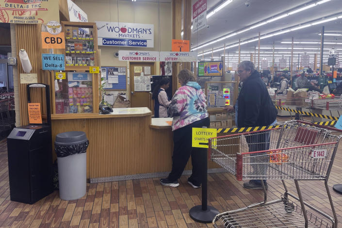 Lottery players Cherrie Spencer and Bruce Homburg stand in line at Woodman's Markets store in Madison, Wis., to purchase Powerball tickets after getting their groceries. The Powerball jackpot recently reached a record high of $1.6 billion. (AP Photo/Harm Venhuizen)