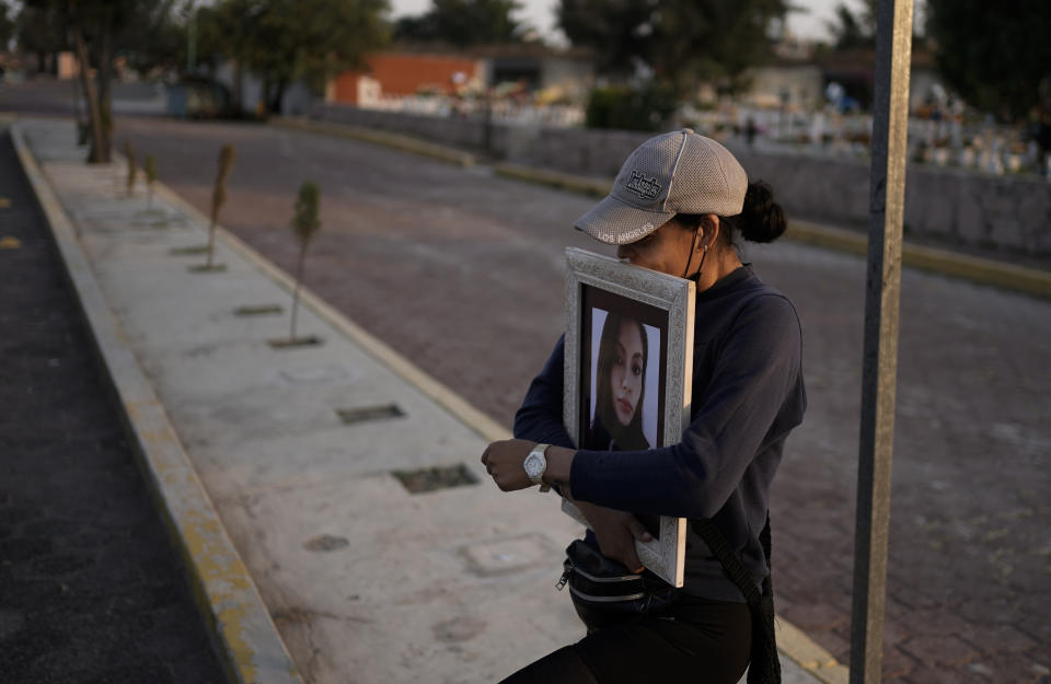 A friend of Monica Citlalli Diaz carries her photo on the sidelines of her funeral at a cemetery in Ecatepec, State of Mexico, Mexico, Friday, Nov. 11, 2022. The 30-year-old English teacher became the ninth apparent femicide during an 11-day spate of killings in and around Mexico City from late October to early November. (AP Photo/Eduardo Verdugo)