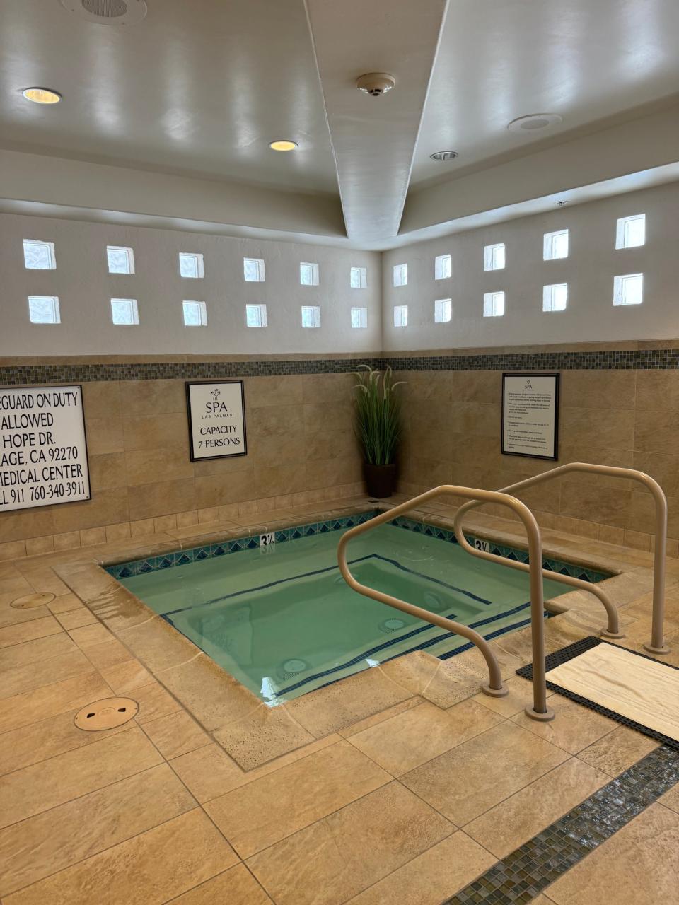 Indoor hotel spa with hot tub, safety signs, and no people present