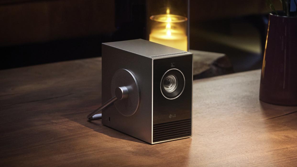  LG CineBeam Qube 4K portable projector sat on wooden table . 