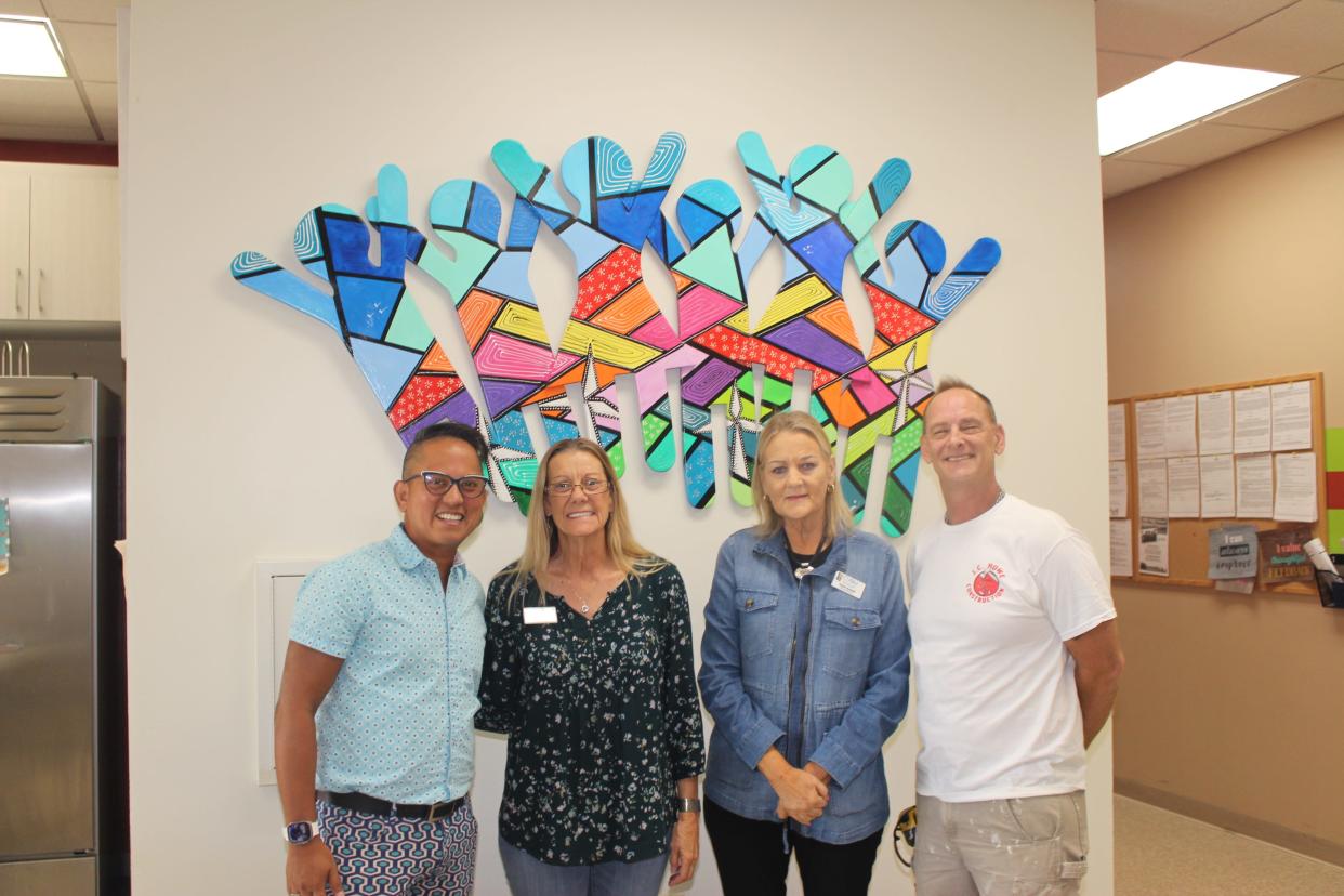 Artist Marconi Calindas; Chris Dentice, CVRM's women’s program manager; Darla Burkett, CVRM's executive director; and artist Jeff Howe pose in front of "Joy,” a vibrant colorful art piece in the Women’s and Family Shelter on Oct. 12, 2023.