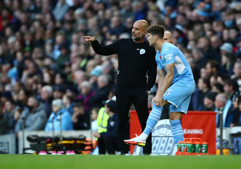 Manchester City manager Pep Guardiola giving instructions to defender John Stones.
