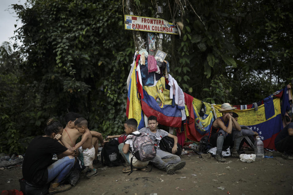 Migrants sit under a sign marking the Panama-Colombia border during their trek across the Darien Gap, Tuesday, May 9, 2023. The image was part of a series by Associated Press photographers Ivan Valencia, Eduardo Verdugo, Felix Marquez, Marco Ugarte Fernando Llano, Eric Gay, Gregory Bull and Christian Chavez that won the 2024 Pulitzer Prize for feature photography. (AP Photo/Ivan Valencia)