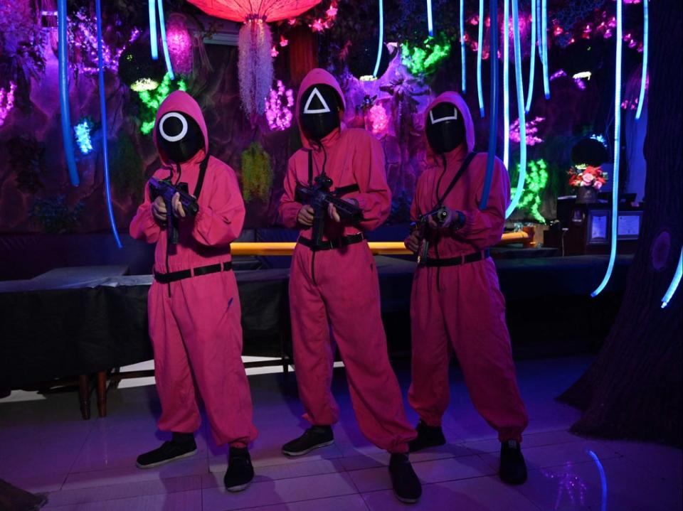 Waiters dressed in outfits from the Netflix series Squid Game pose while playing a game to attract customers at a cafe in Jakarta on October 19, 2021 (AFP via Getty Images)