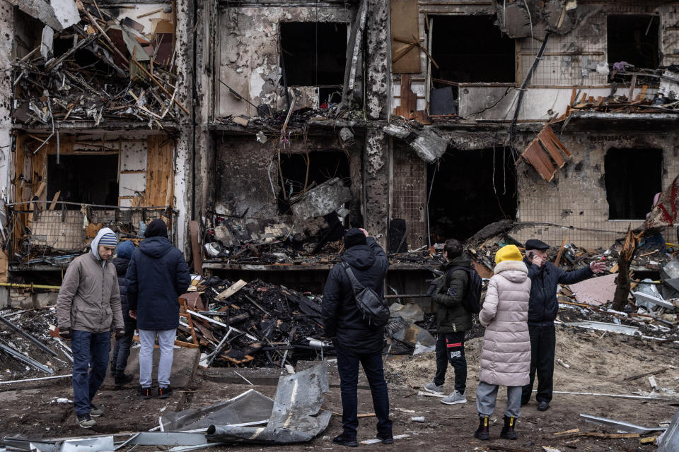 People look at the exterior of a damaged residential block hit by an early morning missile strike on February 25, 2022 in Kyiv, Ukraine. (Chris McGrath/Getty Images)