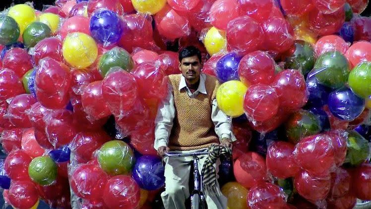 A man rides his bicycle with a huge load of balloons. Photo: Reuters