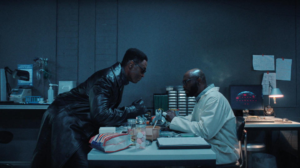 Lance Reddick threatens another Lance Reddick with a knife in the lab in Resident Evil.