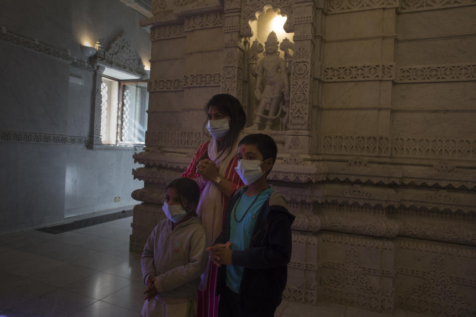 Hindu worshippers offer prayers at the BAPS Shri Swaminarayan Mandir, also known as the Neasden Temple, in London on Friday, July 3, 2020. The temple of carved stone constructed according to ancient Vedic architectural texts usually welcomes thousands of visitors a day but now gets just a trickle of devotees who book appointments online first to keep the crowds down. (AP Photo/Elizabeth Dalziel)