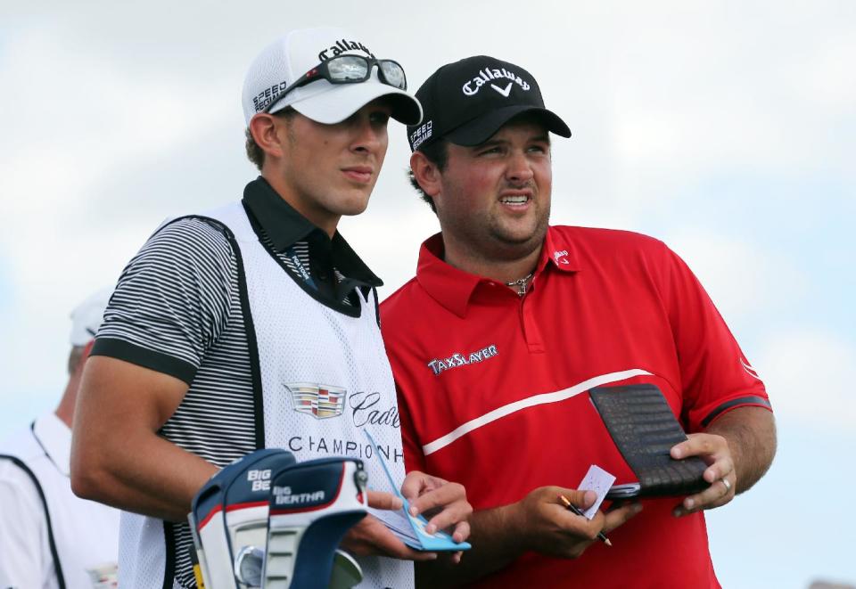 Patrick Reed, right, and his caddie Kessler Karain talk on the third tee during the final round of the Cadillac Championship golf tournament on Sunday, March 9, 2014, in Doral, Fla. (AP Photo/Wilfredo Lee)