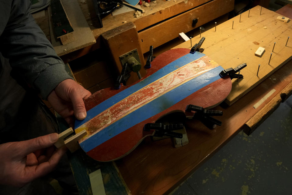 Milan's Opera maximum security prison inmate Pietro (a pseudonym, he doesn't want to reveal his real name) works on the top plate of a violin made from the wood of wrecked migrants' boat in the prison's lab, near Milan, northern Italy, Friday, Feb. 9, 2024. Inmates at Opera used the wood of wrecked boats sailed by migrants across the Sicily Channel to craft the musical instruments that the 'Sea Orchestra' used during their debut at La Scala Opera House in Milan on Monday, Feb. 12, 2024. The violins, violas and cellos played by the Orchestra of the Sea in its debut performance Monday at Milan's famed Teatro all Scala carry with them tales of hardship. (AP Photo/Antonio Calanni)