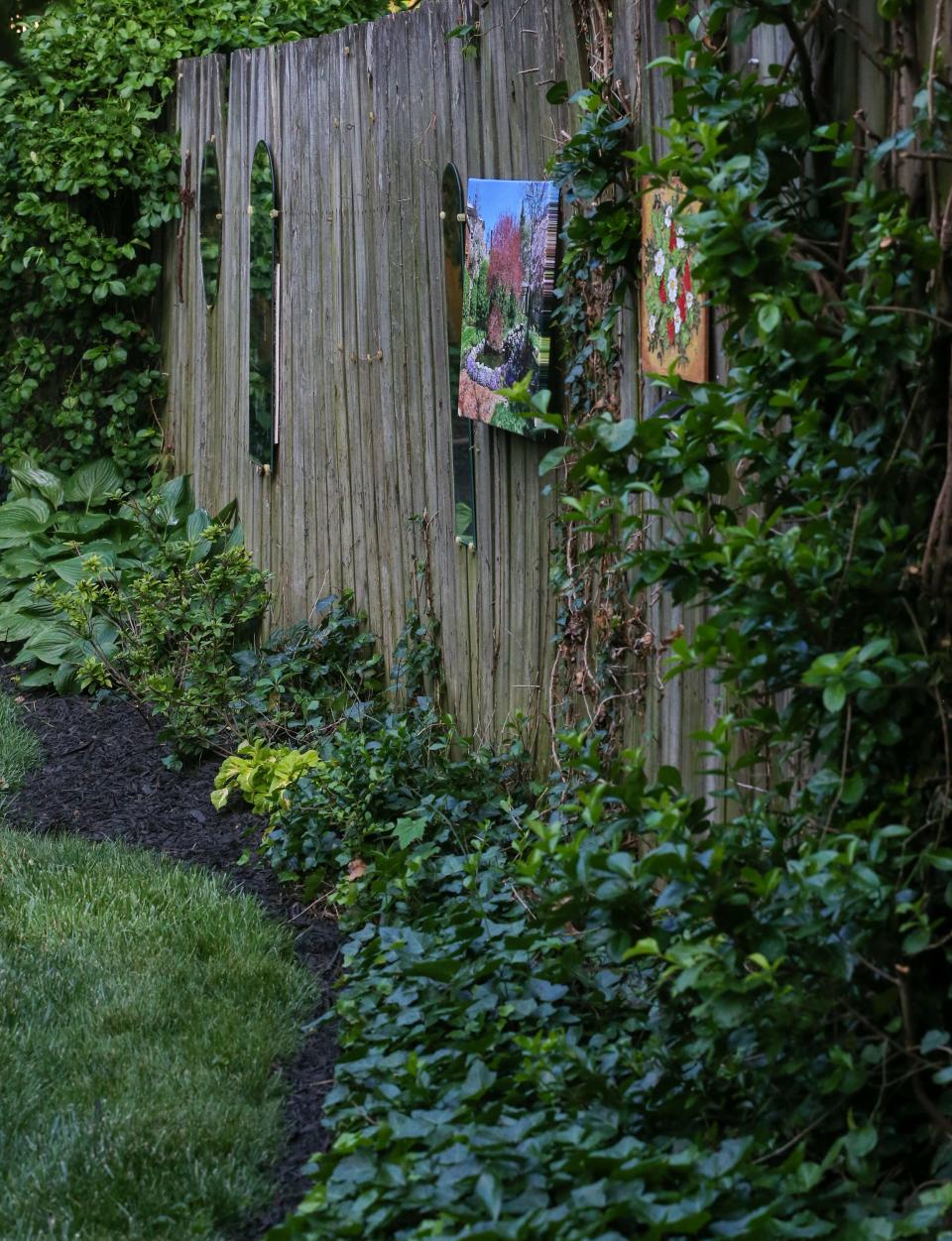 Mirrors and paintings along the fence in the backyard garden of Bill and Becky Medley.