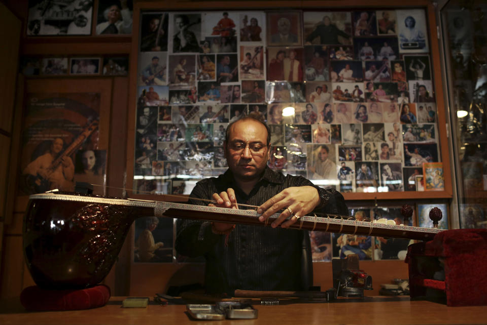 Indian traditional instrument craftsman Sanjay Sharma places a fret on a sitar at his store Riki Ram's Music in New Delhi, India, Thursday, Dec. 13, 2012. For close to a 100 years Sharma's family has created musical instruments for legendary Indian musicians. But none more famous than sitar virtuoso Ravi Shankar who died Tuesday at age 92. Described as "the godfather of world music" by Beatle George Harrison, Shankar introduced millions of Westerners to the sitar and the centuries-old traditions of Indian classical music. (AP Photo/Kevin Frayer)