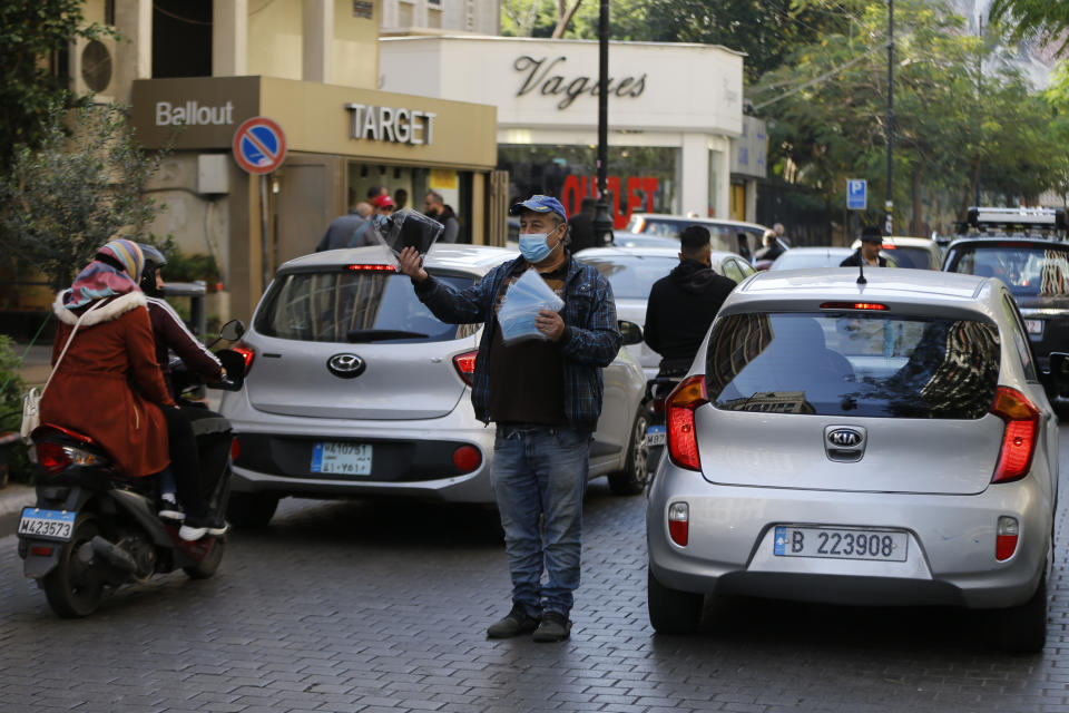 A street vendor wearing a mask to help stop the spread of the coronavirus sells face masks in Beirut, Lebanon, Monday, Jan. 4, 2021. Lebanon is gearing up for a new nationwide lockdown, as officials vowed Monday to take stricter measures against the coronavirus following the holiday season, which saw a large increase in infections and caused jitters in the country's already-battered health sector. (AP Photo/Bilal Hussein)