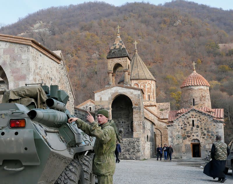 A service member of the Russian peacekeeping troops stands next to a military vehicle at Dadivank monastery in Kalbajar district