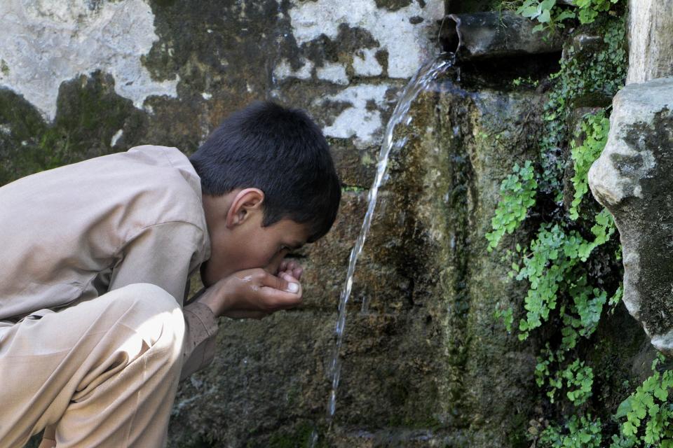 A boy drinks water from a line connected with a waterfall on the outskirts of Mingora, the main town of Pakistan's Swat valley, Friday, May 19, 2023. The flooding in Pakistan killed at least 1,700 people, destroyed millions of homes, wiped out swathes of farmland, and caused billions of dollars in economic losses. In Khyber Pakhtunkhwa, residents had to rely on contaminated water, so now authorities are taking steps to prepare for the next disaster. (AP Photo/Naveed Ali)