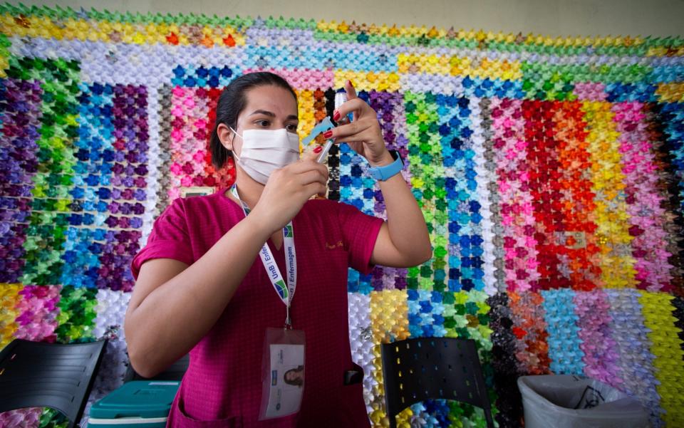 A health professional prepares a vaccine in front of a panel in honour of the victims of Covid in Brasilia Ceilandia - Getty