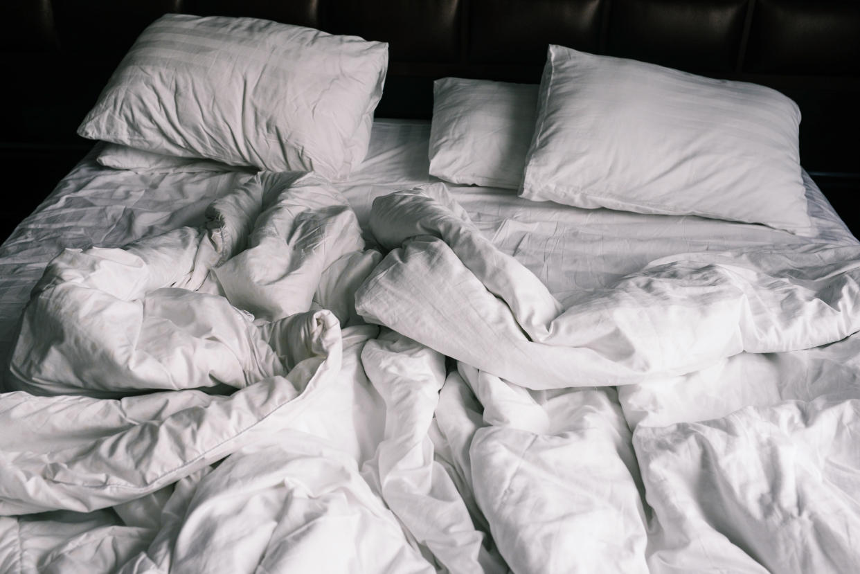 Unmade empty bed with white linens. Sheets and pillows in the apartment or hotel after a night's sleep. Dirty and crumpled blanket in the hotel.�