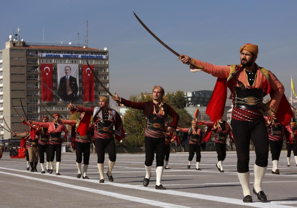 The Seymens, representing Ankara local militia who welcomed Mustafa Kemal Atuturk in Ankara in 1919 as Atuturk arrived to organize the the Independence war that led to the foundation of Turkish republic, march during the celebrations for the 90th anniversary of republic in Ankara, Turkey, Tuesday, Oct. 29, 2013. A poster of Atuturk hangs from a building in the background.(AP Photo/Burhan Ozbilici)
