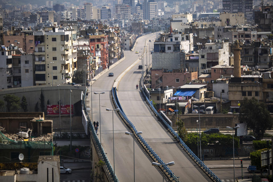 People walk on a highway that is almost empty of cars, east Beirut, Lebanon, Sunday, March 15, 2020. Lebanon has been boosting precautionary measures including halting flights from several countries, closing all restaurants and nightclubs and tightening measures along the border with neighboring Syria. (AP Photo/Hassan Ammar)