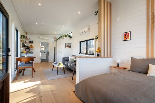 The floors are lined in engineered hardwood. Solid oak is used for the waist-high bar and slats along the white shiplap walls to help separate the bedroom from the rest of the interior.