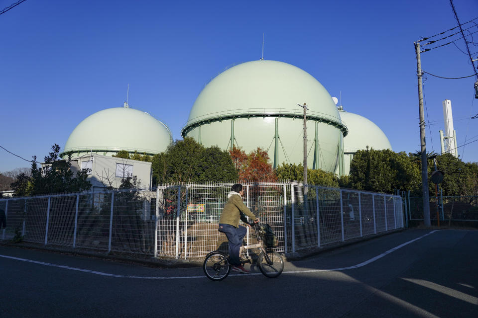 A cyclist travels past Tokyo Gas Co. storage tanks at the company's Setagaya facility in Tokyo, Japan, on Monday, Dec. 25, 2023.  Photographer: Toru Hanai/Bloomberg