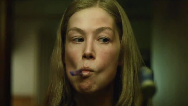 Rosamund Pike as Amy Elliott Dunne with a toothbrush on her mouth in the film Gone Girl.