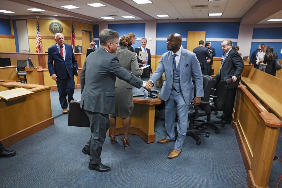 Brian Rafferty, left, who is defending Sidney Powell, and Fulton County proscutor Nathan Wade, right, shake hands after Superior Judge Scott McAfee rejected attempts from Ms Powell and Kenneth Chesebro to sever their cases from one another in a Georgia election interference trial. (EPA)